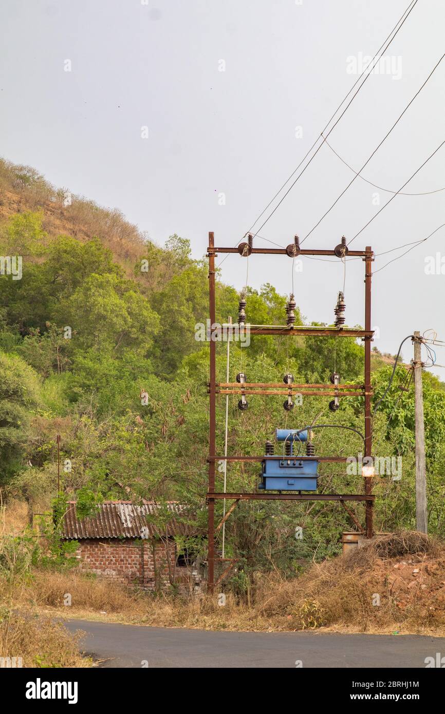 an electrical transformer in a typical indian village, installed on a roadside. Stock Photo