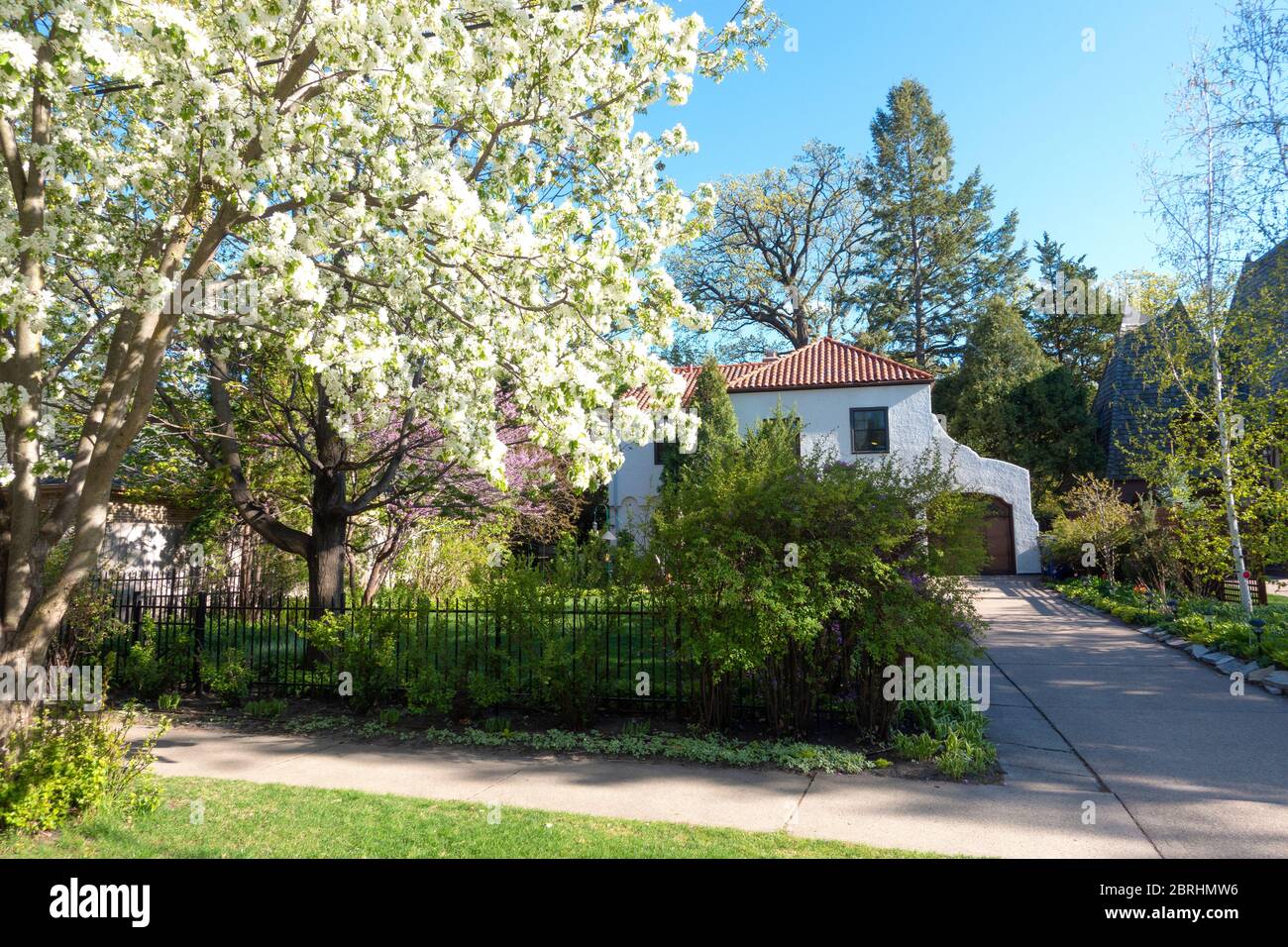 Beautiful home with red tile roof and apple tree filled with blossoms. St Paul Minnesota MN USA Stock Photo