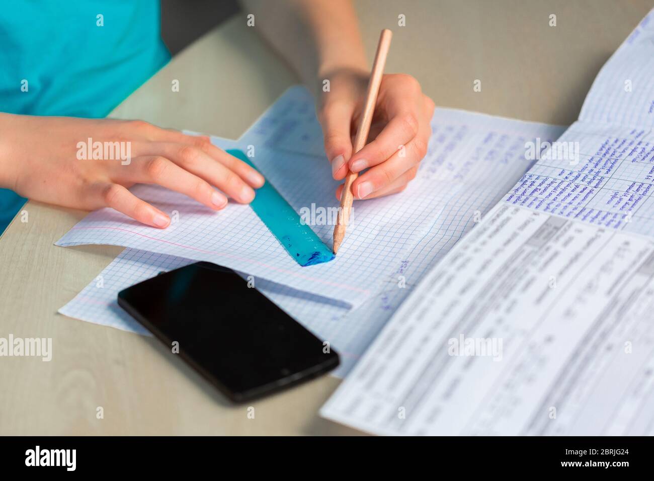 Teenage girl left-handed drawing with a ruler, close up on hands. Studying, education and exam concept Stock Photo