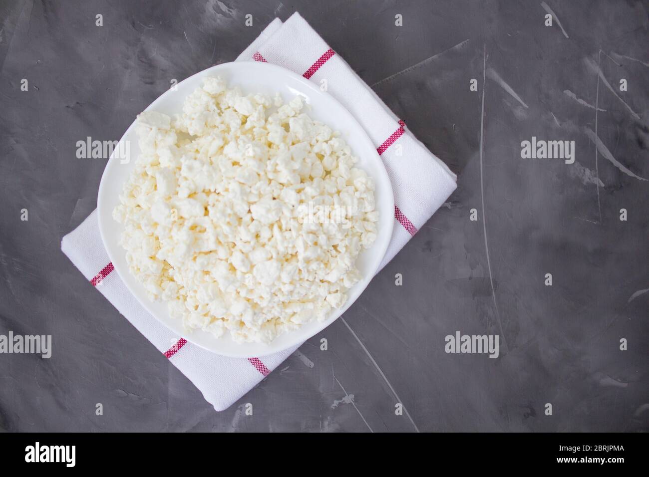 Plate of fresh cottage cheese on a concrete background. Healthly food. Organic cottage cheese. Keto diet. Macro. View from above. Copyspace Stock Photo