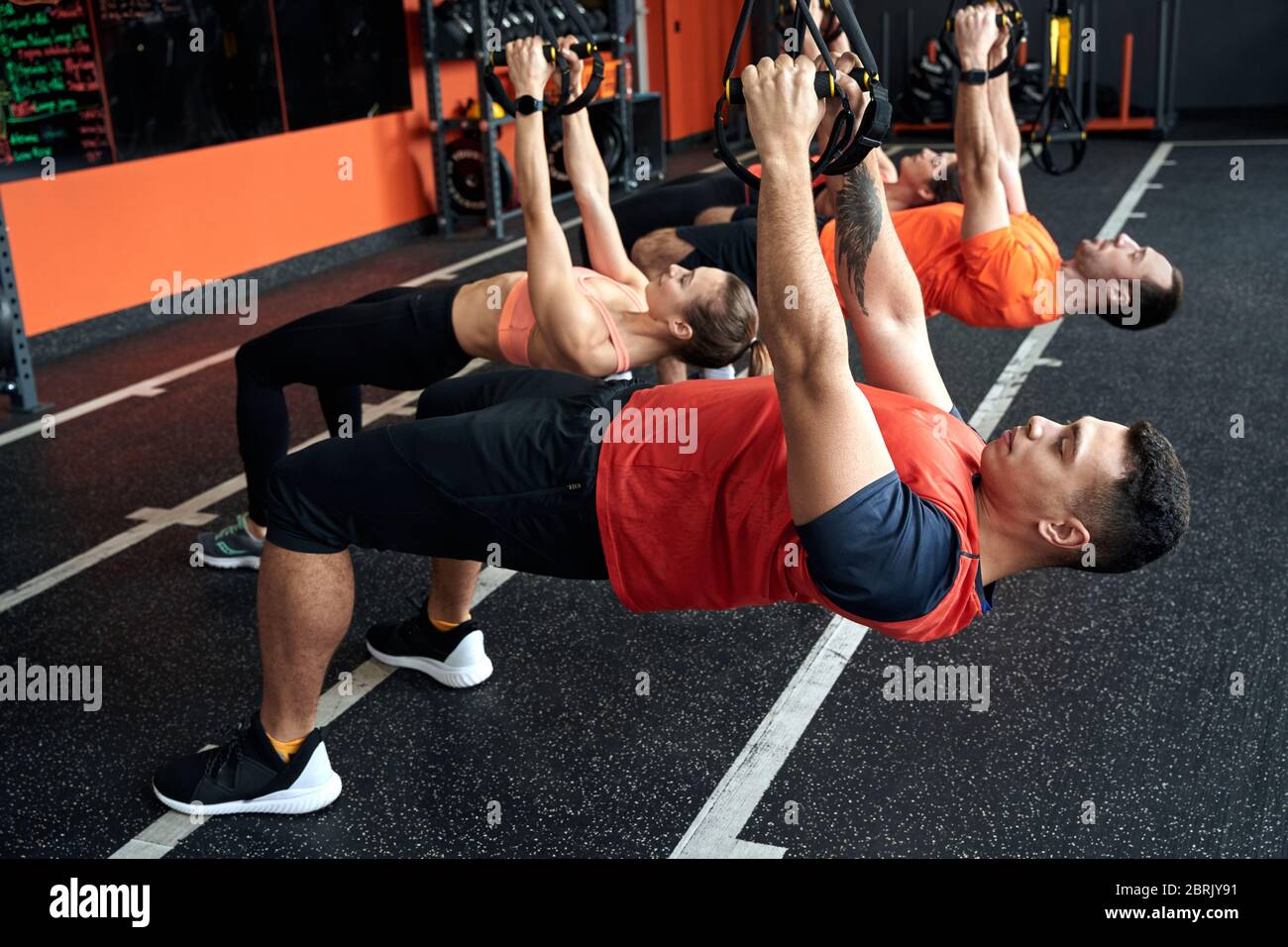 Sporty Lifestyle. Young people doing low row TRX exercise at gym breathing  concentrated Stock Photo - Alamy