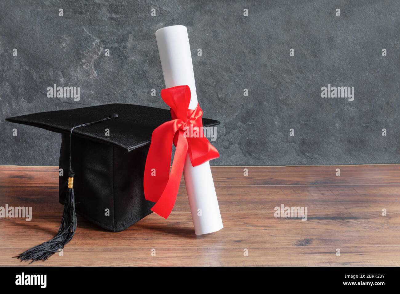 Academic cap and graduation diploma scroll and tied with red ribbon on ...