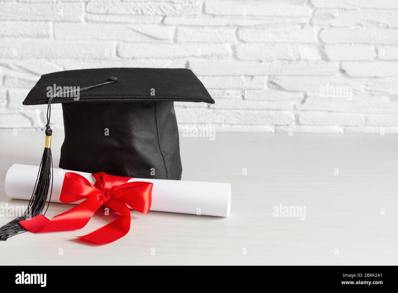 Academic cap and graduation diploma scroll and tied with red ribbon on ...