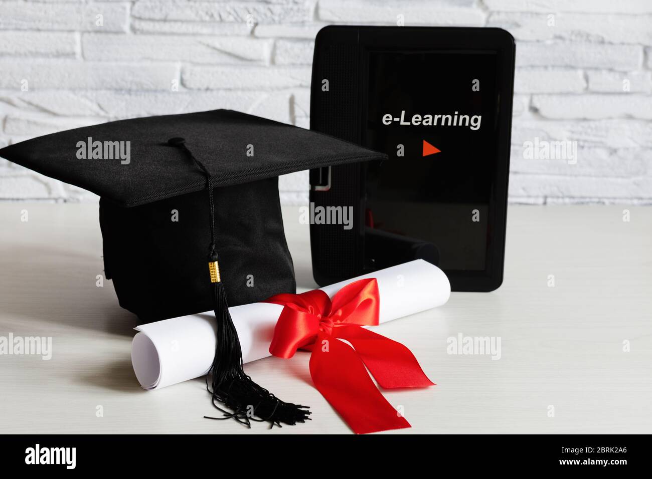 Academic cap and graduation diploma scroll and tied with red ribbon and ...