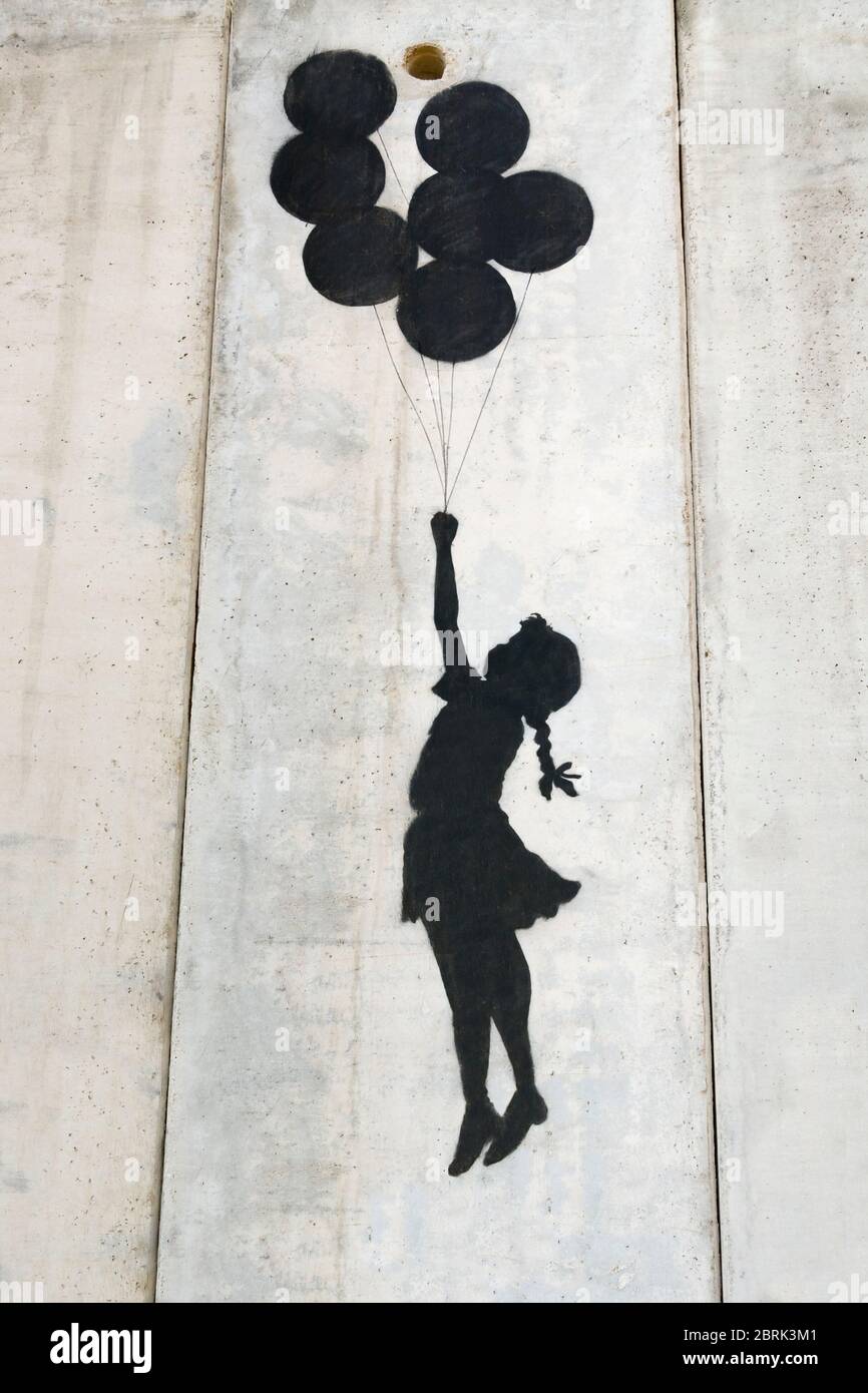 Banksy girl flying with balloons graffiti on the separation wall, Palestine Stock Photo