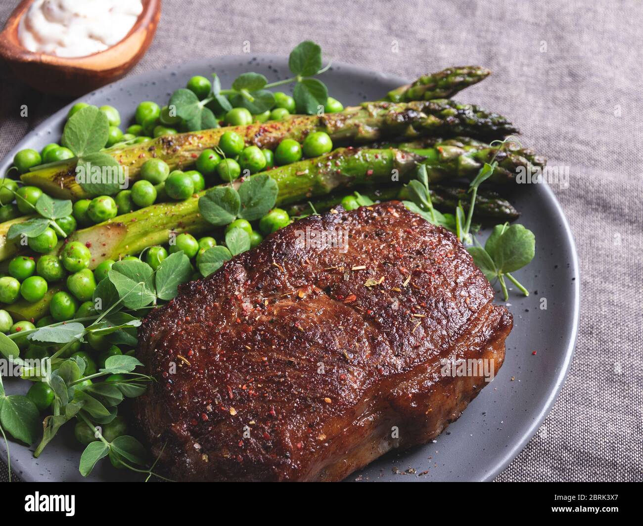 roasted beef steak, mutton with asparagus green peas on a plate, white sauce Stock Photo