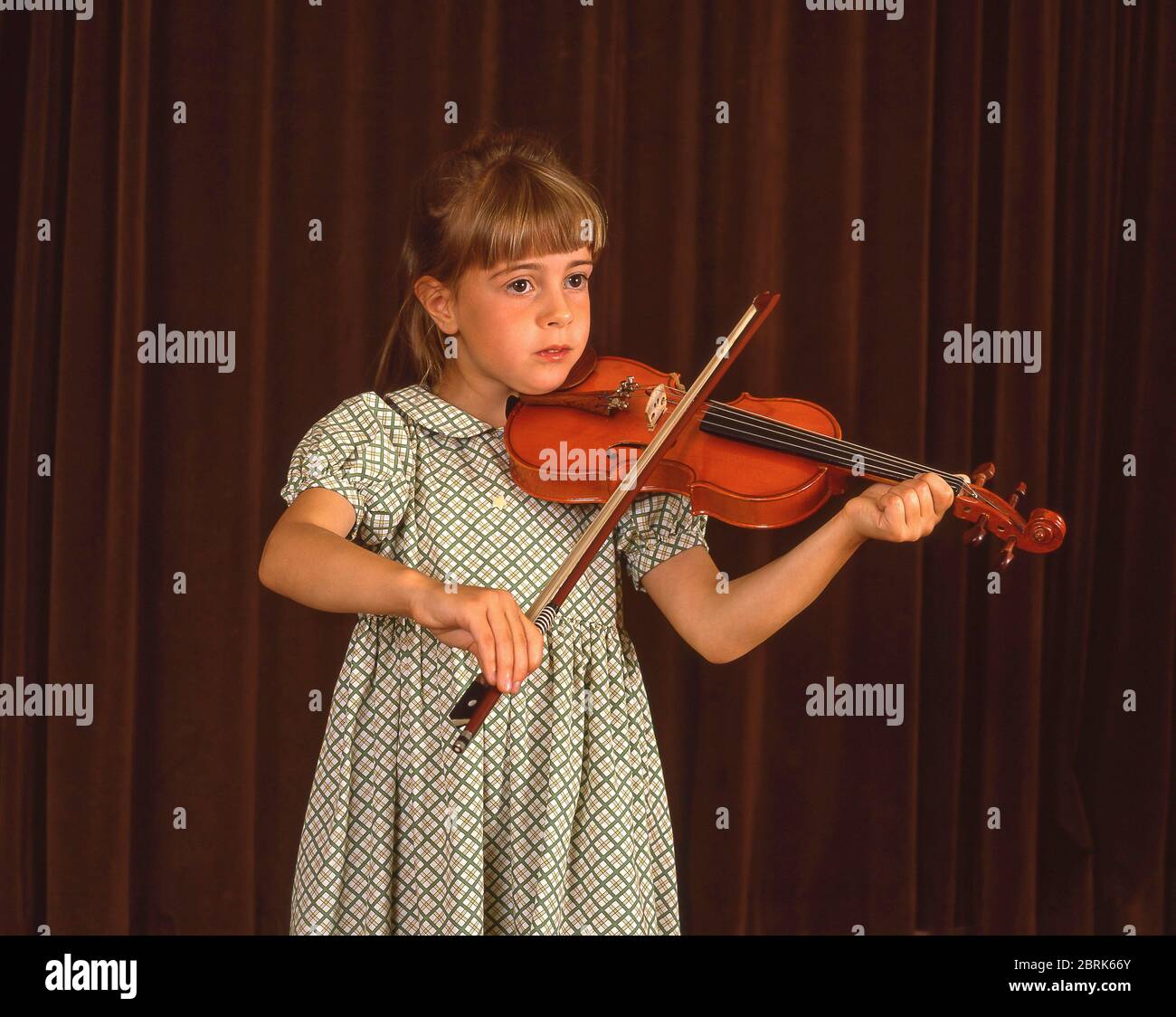 Young primary schoolgirl playing violin in school orchestra, Surrey, Berkshire, England, United Kingdom Stock Photo