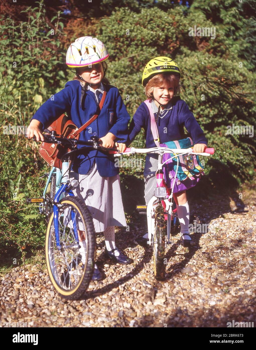 Sisters leaving for primary school on bicycles, Winkfield, Berkshire, England, United Kingdom Stock Photo