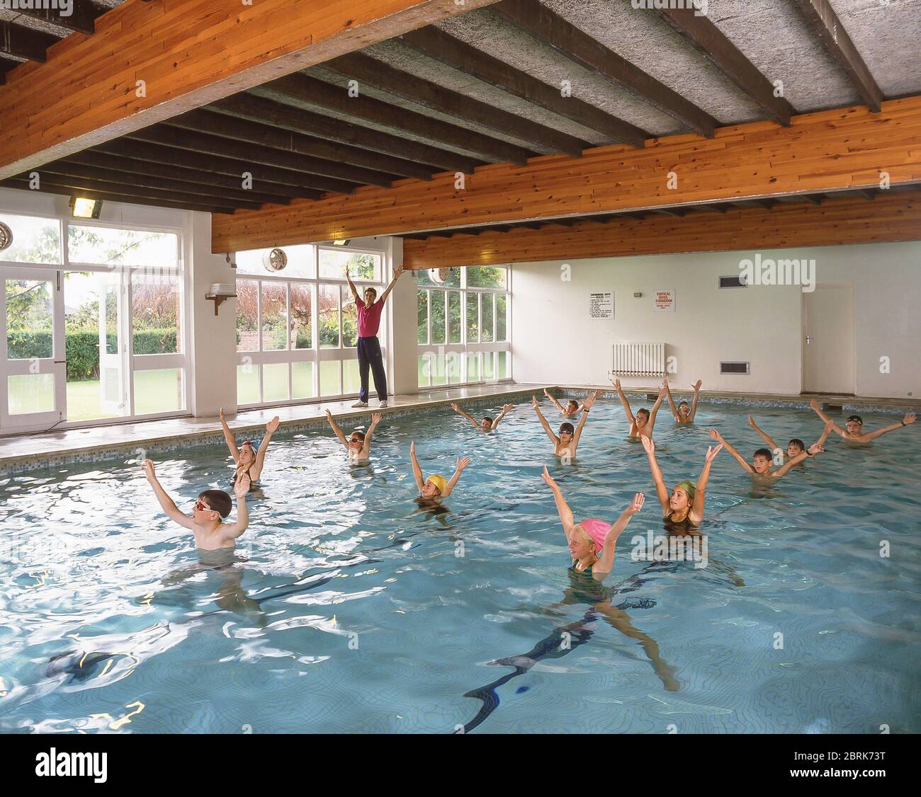 School children exercising in indoor swimming pool, West Sussex