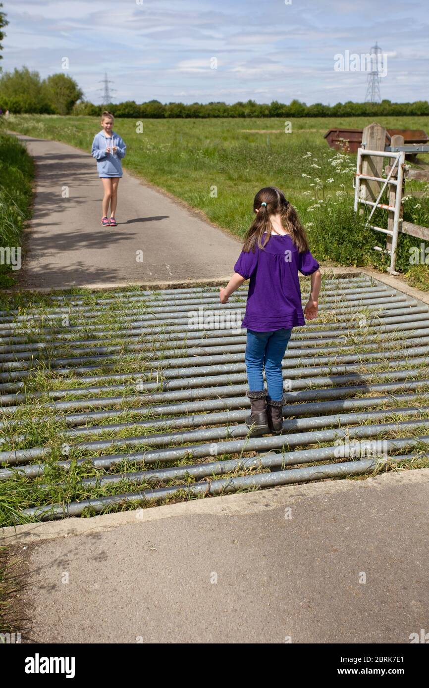 Young girl walking across a cattle grid, Uk Stock Photo