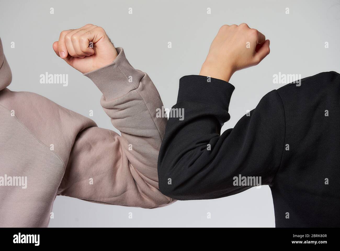 A new way of greeting to avoid the spread of coronavirus. A boy and a girl in sweatshirts bump elbows Instead of greeting with a hug or handshake. Stock Photo