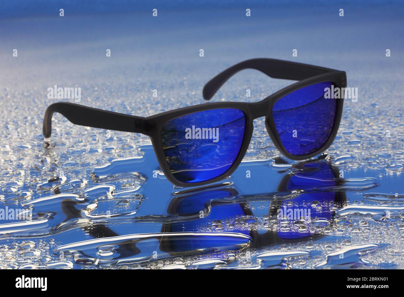 Blue sunglasses with black frames on water reflection with selective focus Stock Photo