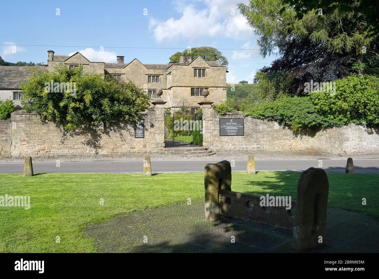 Eyam Hall in the Peak District, Derbyshire England UK, Jacobian styled historic, grade 2 listed building. Village stocks in foreground. Stock Photo