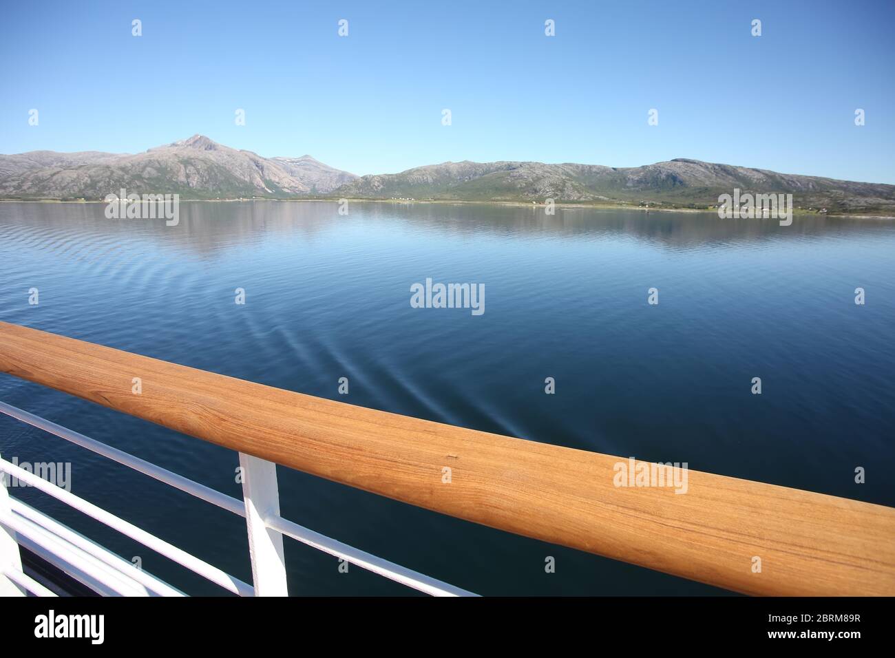 Deck & railing of a ship as it cruises fjords, islands & inside passages; the Andfjorden & Vestfjorden, between Bodo & Hammerfest, Norway. Stock Photo