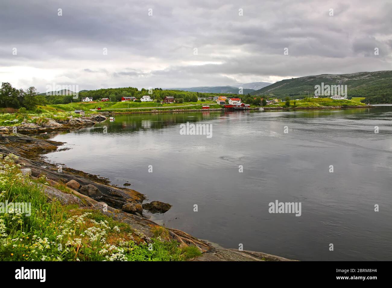 Beautiful landscape along with waters edge, village, church & mountains in the background, Saltstraumen, Municipality of Bodo, Nordland county, Norway. Stock Photo