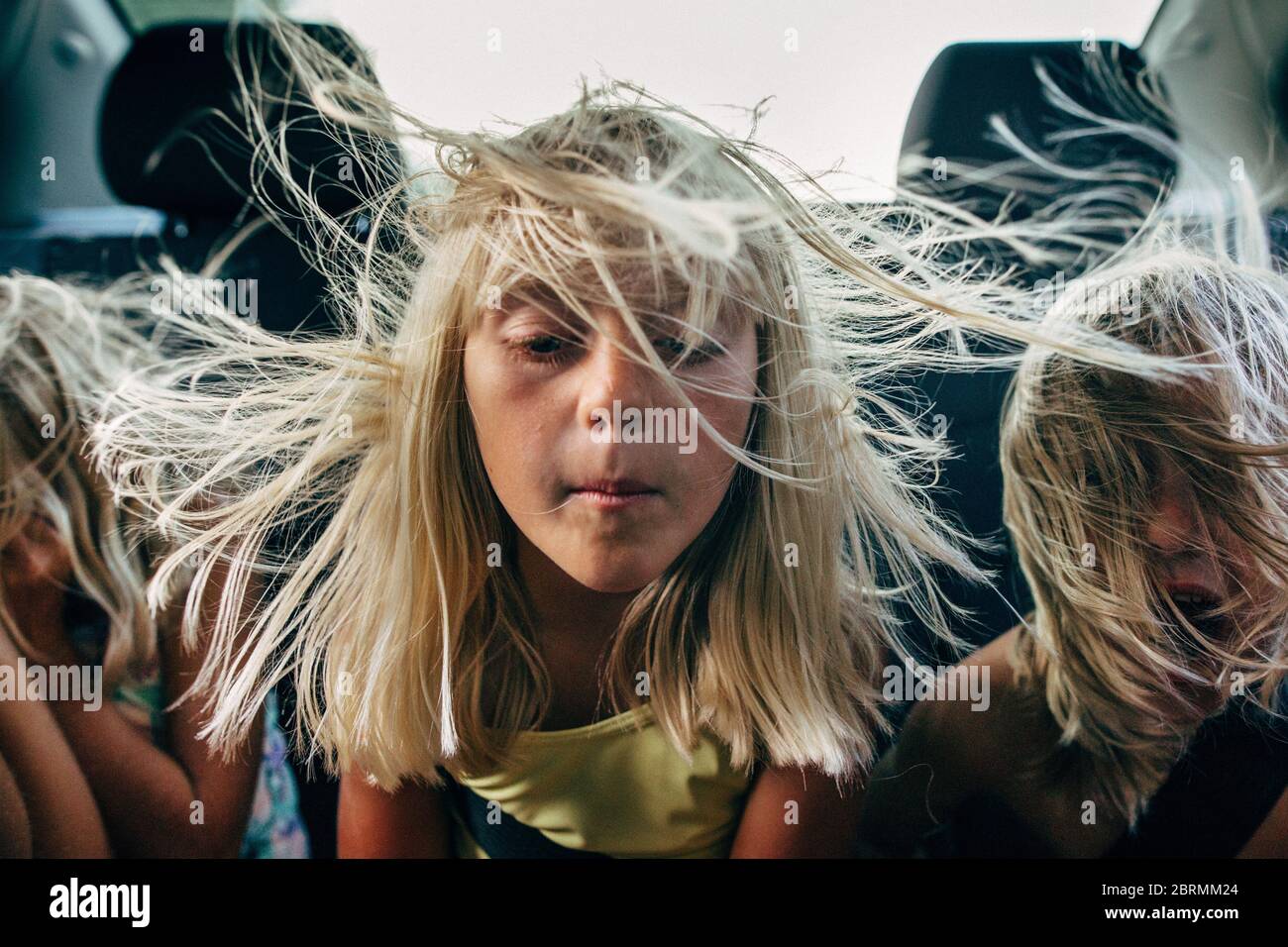 boys and girls in backseat of car with hair blowing in wind Stock Photo