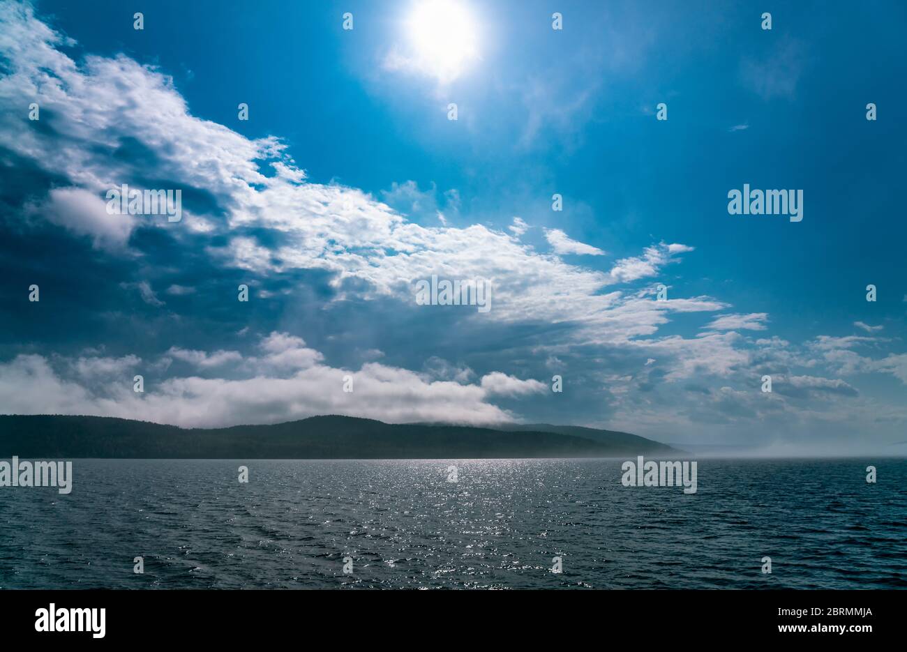 Sea fog laying over the sea disappears under strong morning sun, almost no wind, blue skies Stock Photo