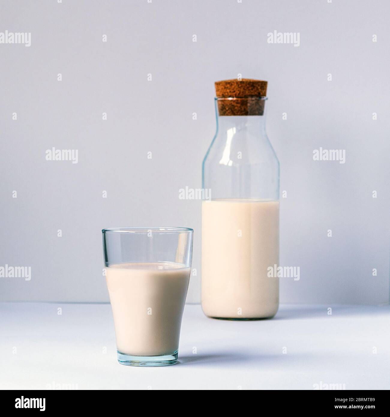 A glass and bottle of non dairy milk on white table. Healthy food concept. Stock Photo