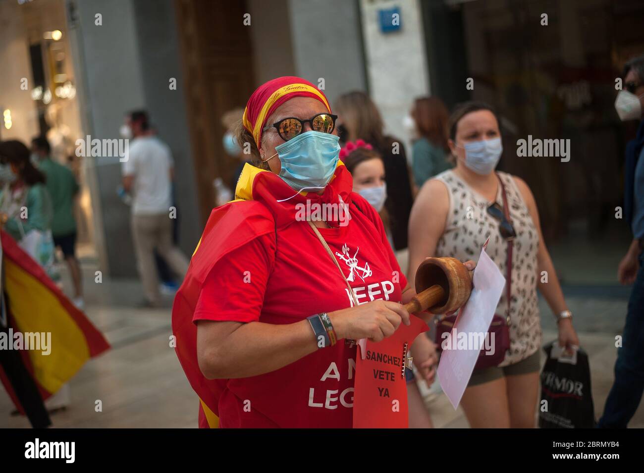 A woman wrapped with a Spanish flag takes part during the demonstration.Several Spaniards have protested against the Spanish government and public management of the Covid - 19 crisis. The far-right party VOX demand the end of confinement and state of emergency because they consider that limit their rights and all Spaniards. Stock Photo