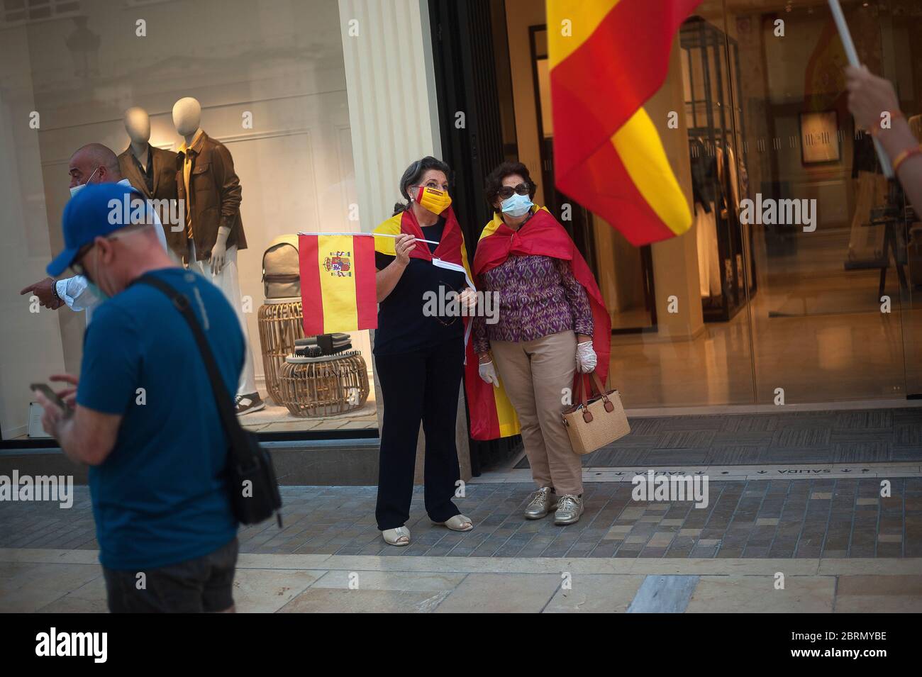 Women wrapped with Spanish flags take part during the protest.Several Spaniards have protested against the Spanish government and public management of the Covid - 19 crisis. The far-right party VOX demand the end of confinement and state of emergency because they consider that limit their rights and all Spaniards. Stock Photo