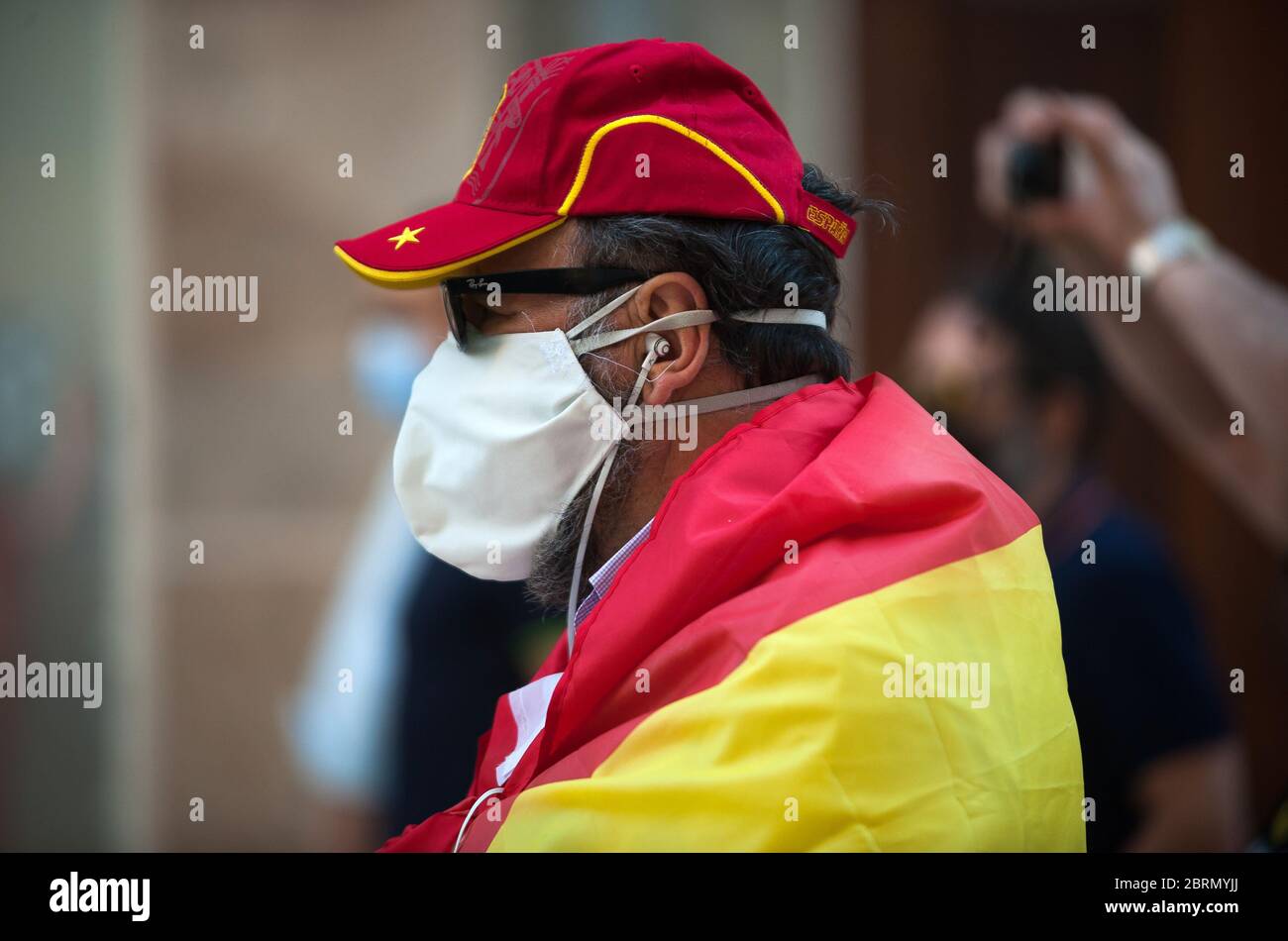 A man wrapped with a Spanish flag takes part during the demonstration.Several Spaniards have protested against the Spanish government and public management of the Covid - 19 crisis. The far-right party VOX demand the end of confinement and state of emergency because they consider that limit their rights and all Spaniards. Stock Photo