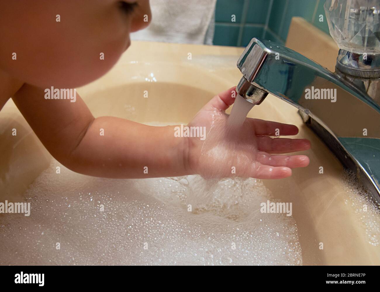 Little boy in a bathroom washing his hands in the sink Stock Photo