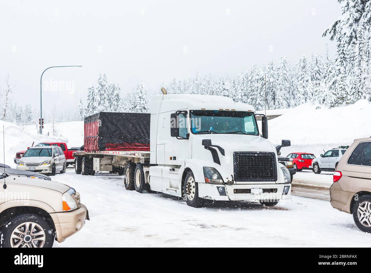 white truck on snow road with traffic jam on snowy day in winter. Stock Photo