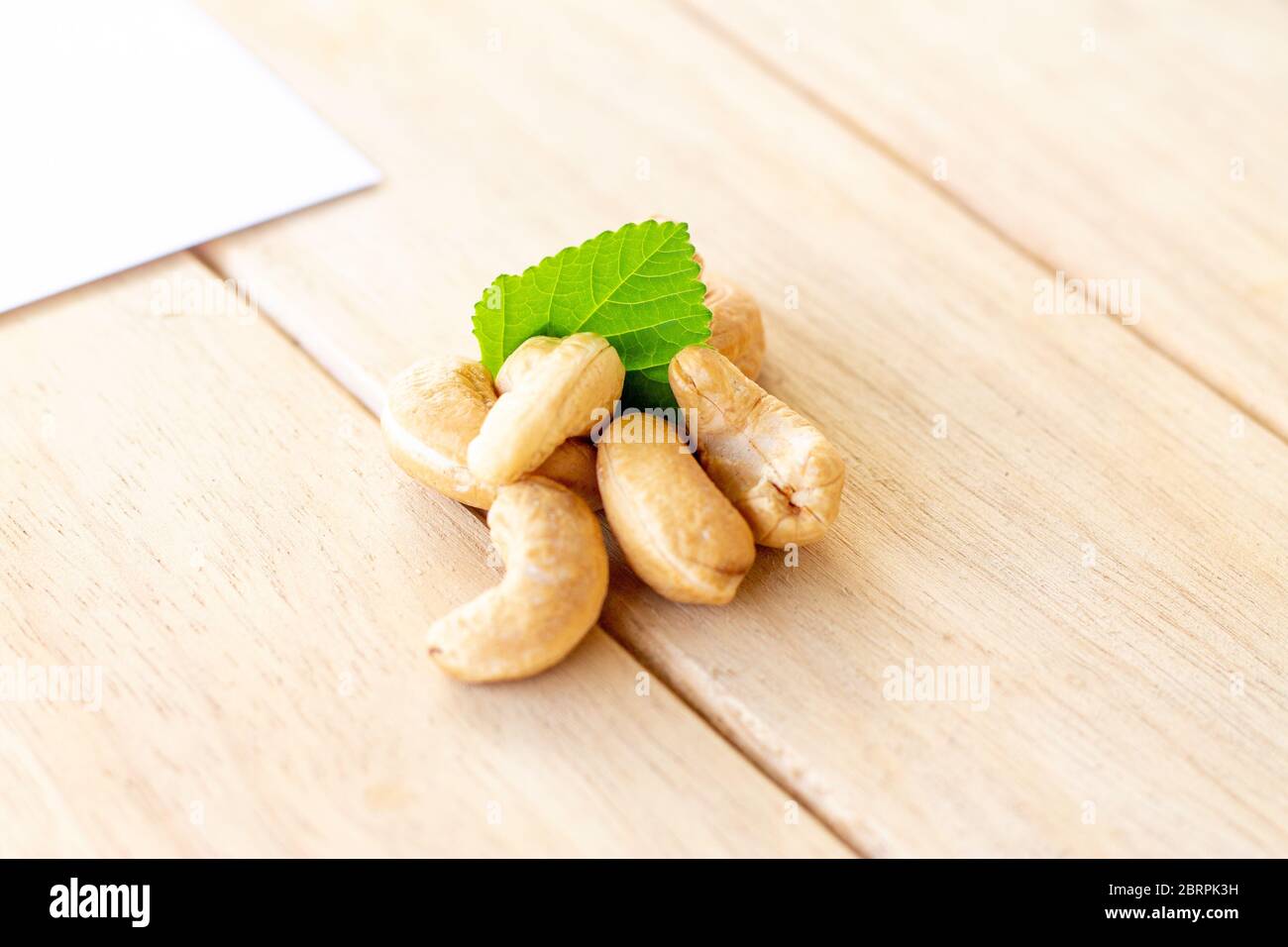 many cashew nut with green leaf on wooden table in studio Stock Photo