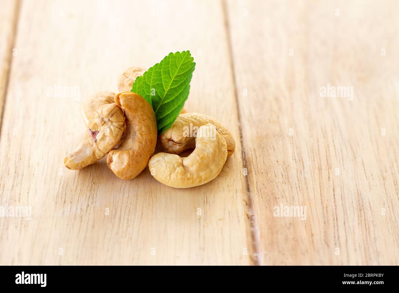 many cashew nut with green leaf on wooden table Stock Photo