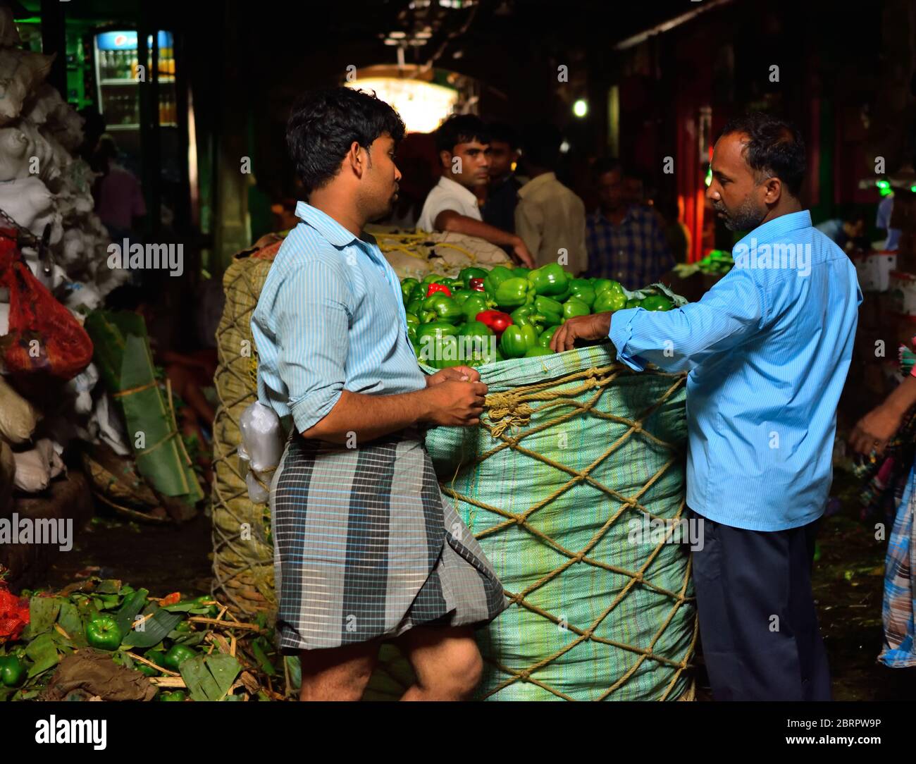 Laborers waiting near a basket full of capsicum at Koley market in Sealdah. Stock Photo