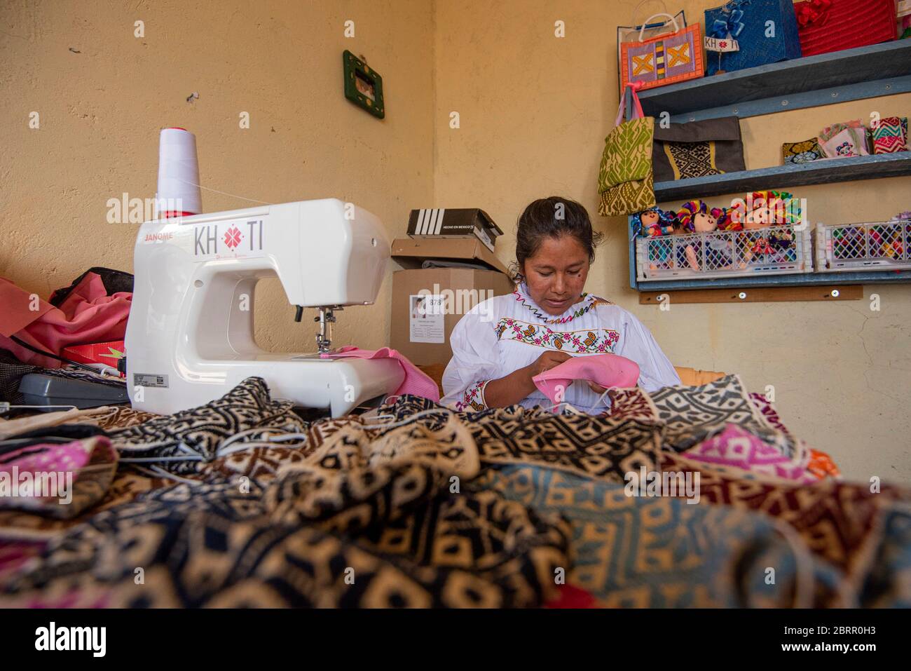 A worker makes re-usable face masks at their office during the coronavirus crisis.About 20 Otomi women from the community of San Idelfonso, in the municipality of Amealco Qro, have changed the direction of their business to face of the Covid-19 pandemic, before this they were dedicated to making handcrafted napkins and dolls and now, due to the Coronavirus crisis, their direction has changed to making handcrafted mouth covers, all with the theme that represents them as an indigenous people of the state. Stock Photo
