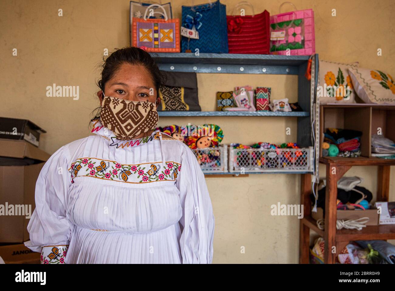 A worker wears one of their re-usable face masks during the coronavirus crisis.About 20 Otomi women from the community of San Idelfonso, in the municipality of Amealco Qro, have changed the direction of their business to face of the Covid-19 pandemic, before this they were dedicated to making handcrafted napkins and dolls and now, due to the Coronavirus crisis, their direction has changed to making handcrafted mouth covers, all with the theme that represents them as an indigenous people of the state. Stock Photo