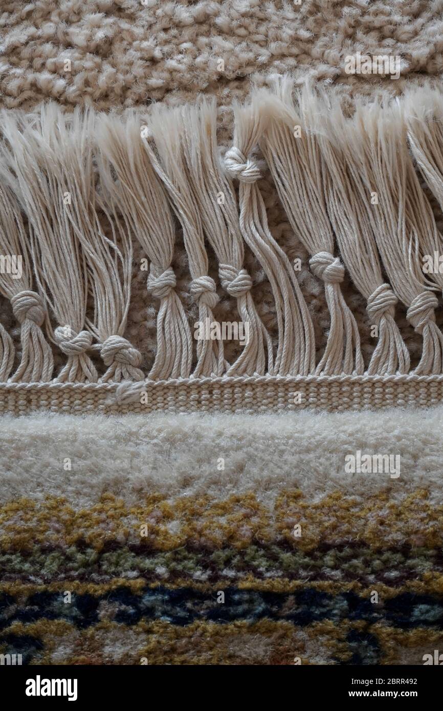 Close up of a section of a cotton fringe on an old wool rug; fringe was hand knotted, knots at varying levels, as seen from above the rug. Stock Photo