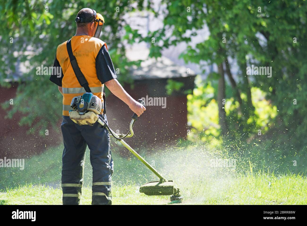 worker cutting grass in garden with the weed trimmer Stock Photo
