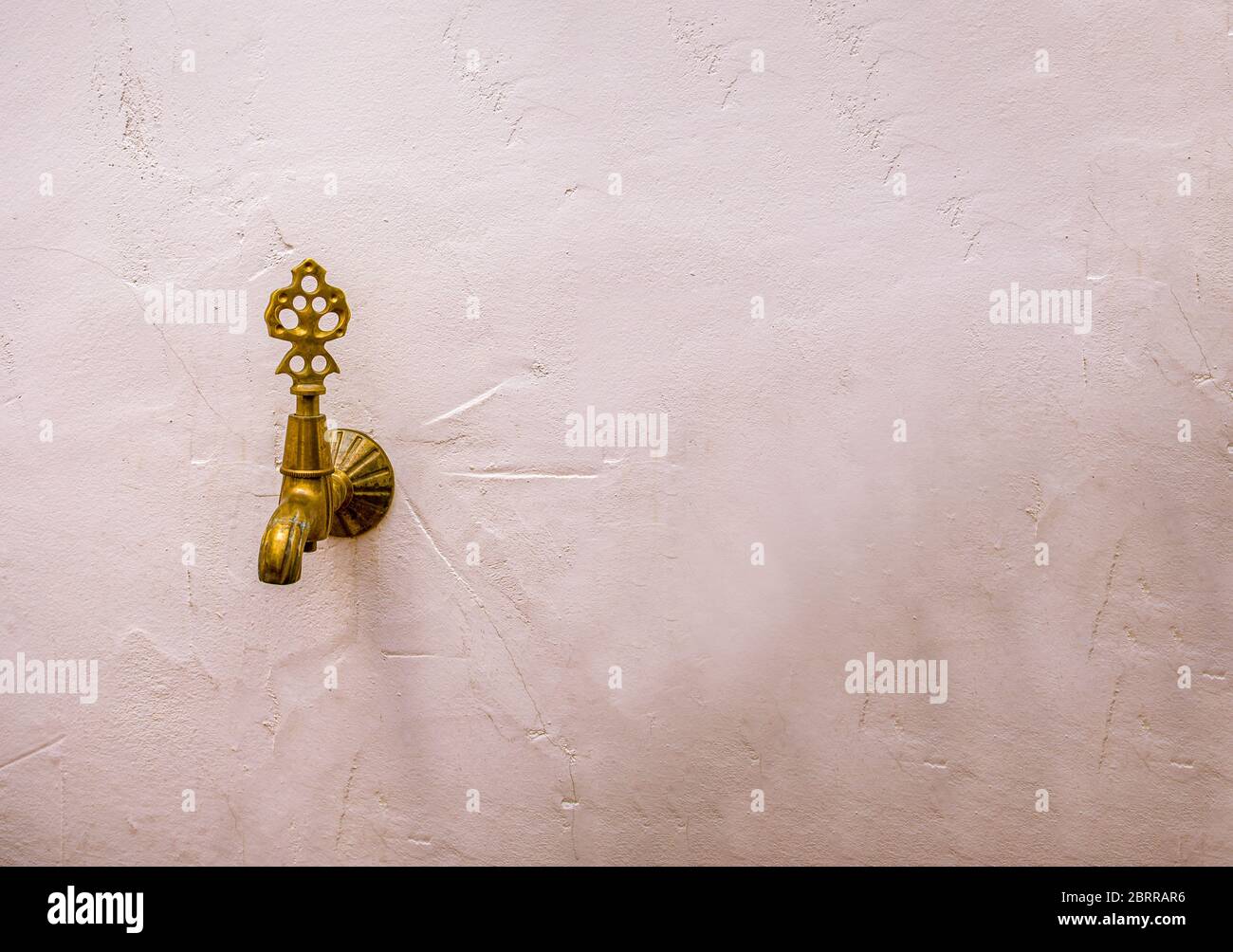 Antique bronze faucet on a white wall. Stock Photo