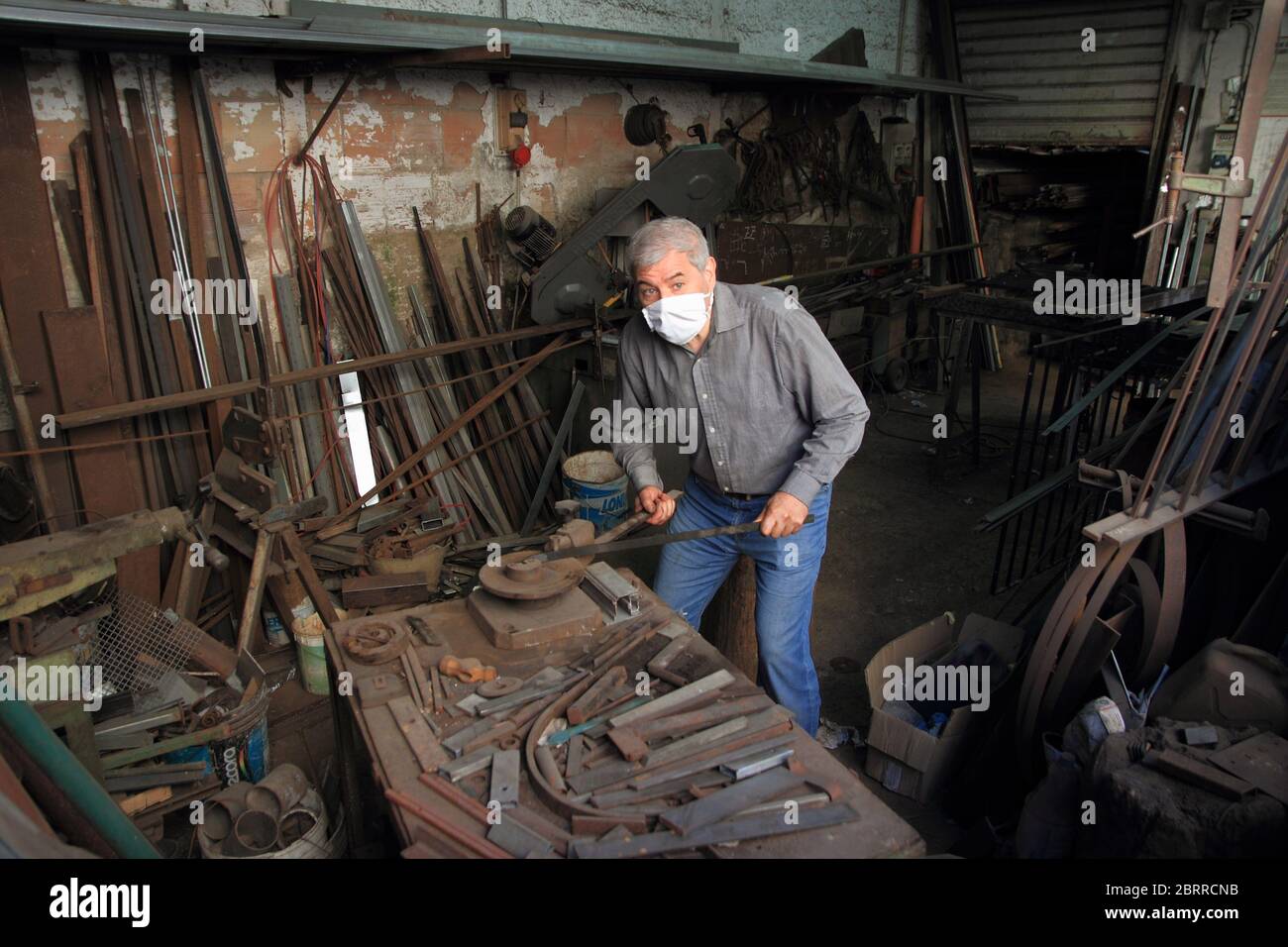 A blacksmith inside his workshop works iron to be welded to a balcony of a house under construction . Stock Photo