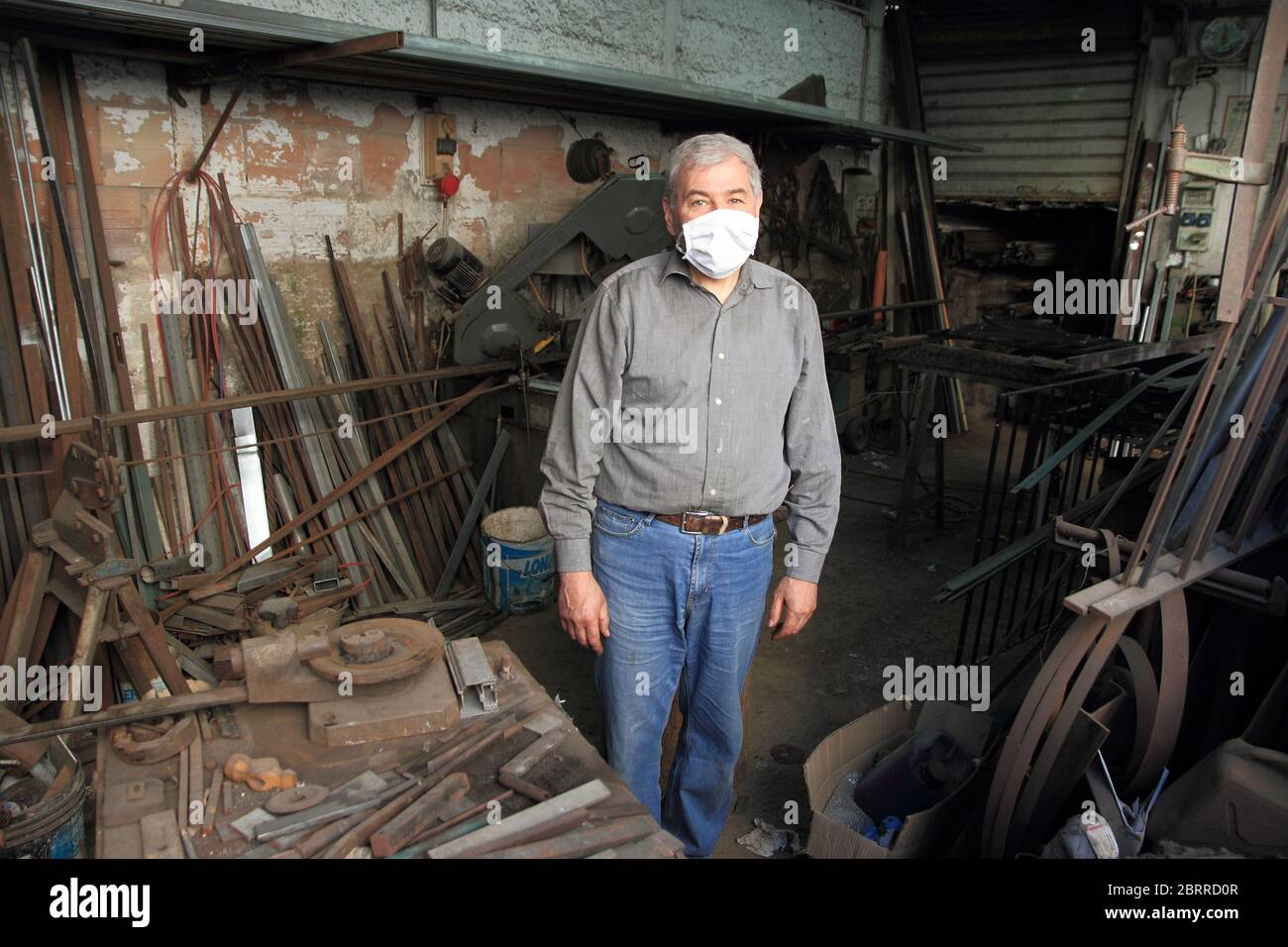 A blacksmith inside his workshop works iron to be welded to a balcony of a house under construction . Stock Photo