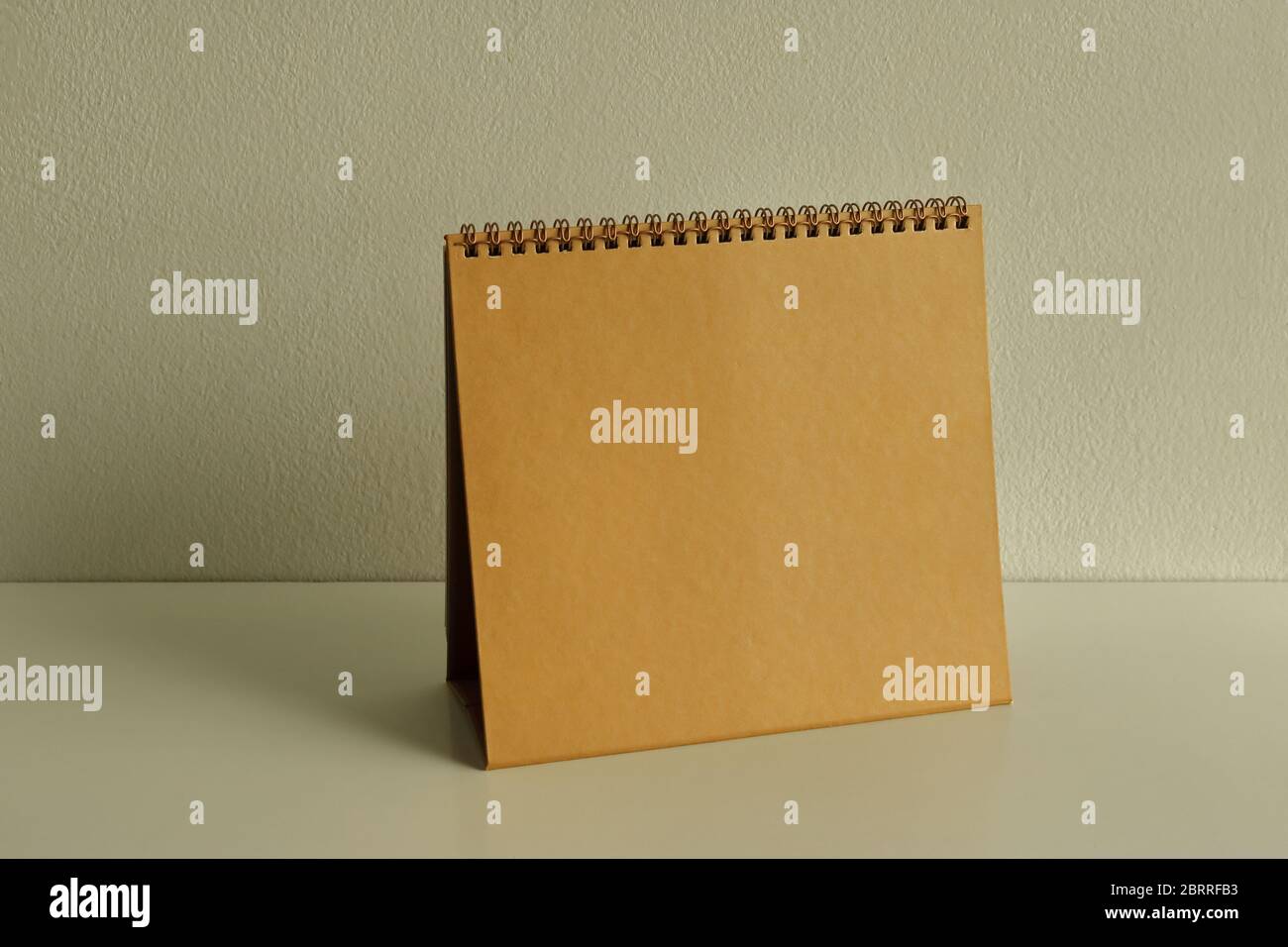 Empty golden spiral binding desk calendar placed on white wooden table