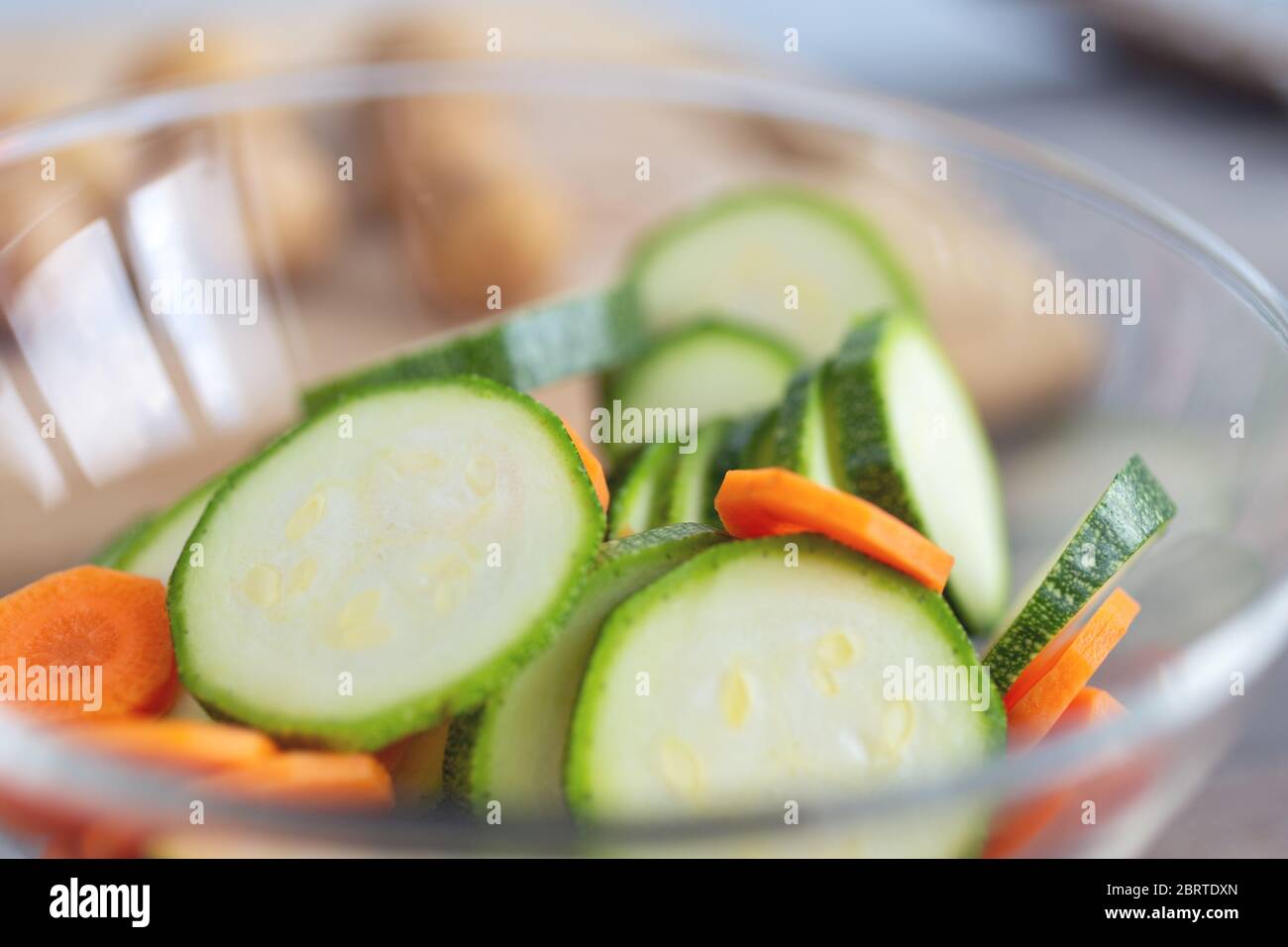 Close up of green zucchini cucumber and carrot slices in a bowl. Healthy food preparation concept Stock Photo
