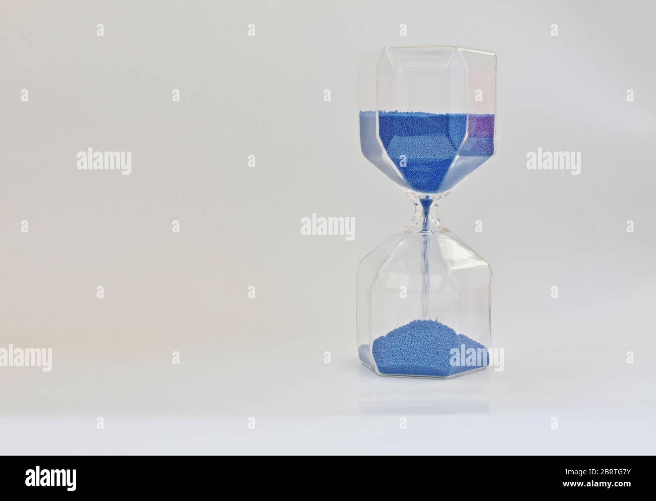 Old time measurement instrument with blue running sand. (hourglass, clepsydra) Stock Photo