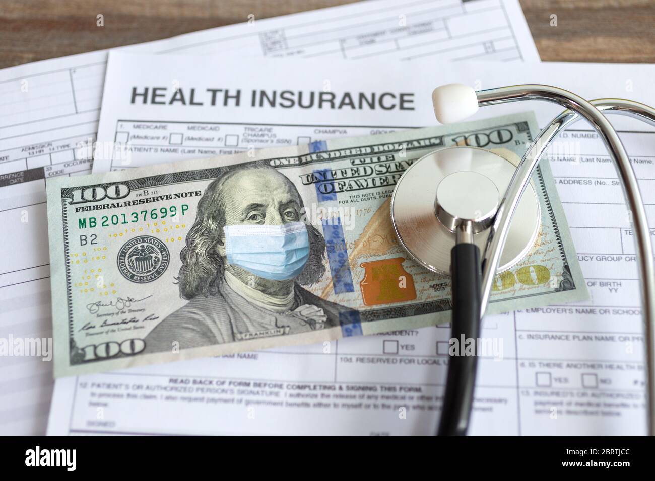 One hundred us dollar with face mask on insurance paper bill. Health care cost during coronavirus covid outbreak concept Stock Photo
