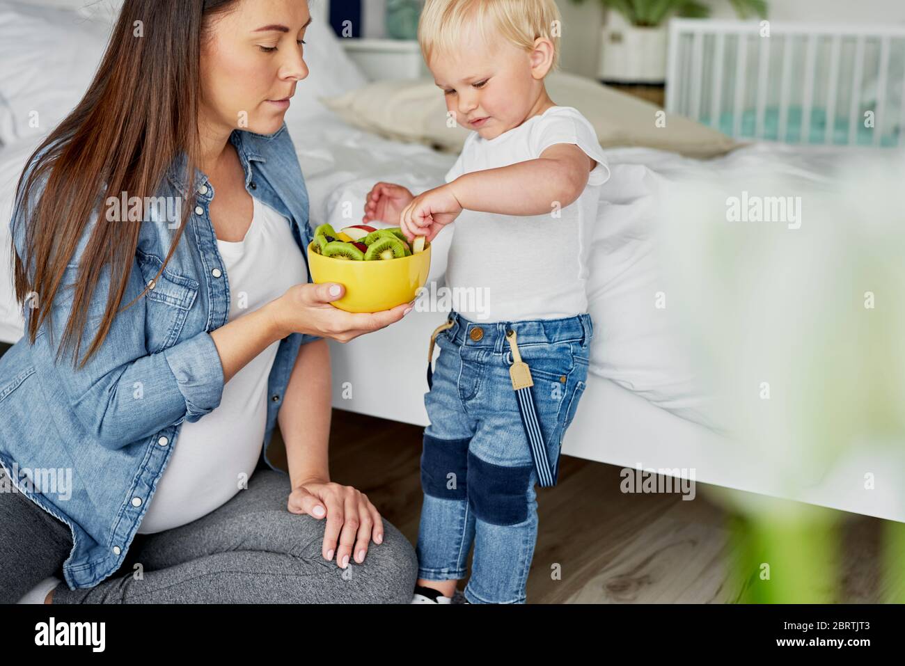 Toddler picking up fruit from the bowl Stock Photo