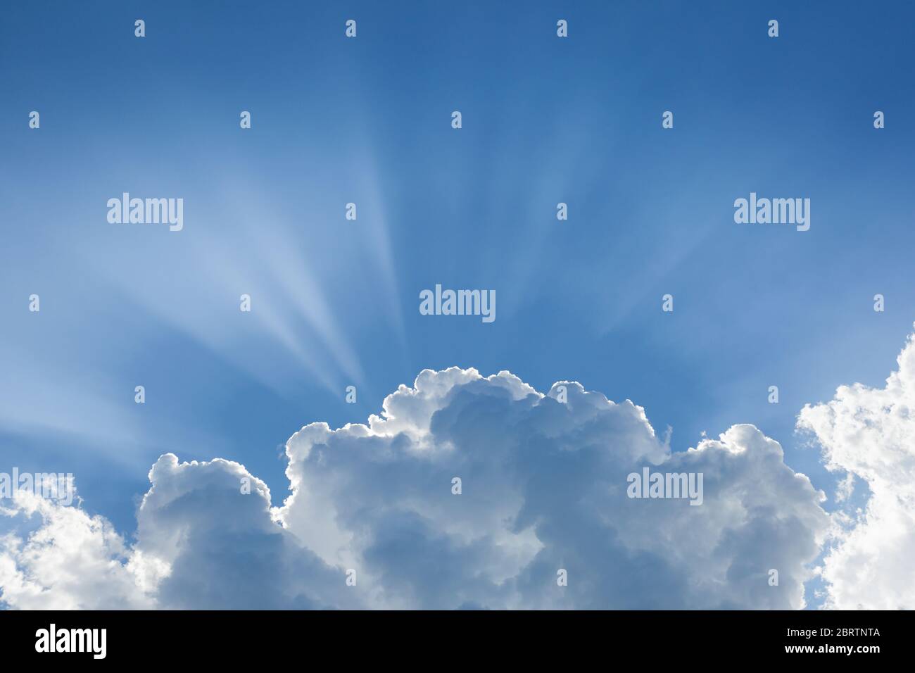 Blue sky with sunbeams behind big white cloud. The concept of paradise ...