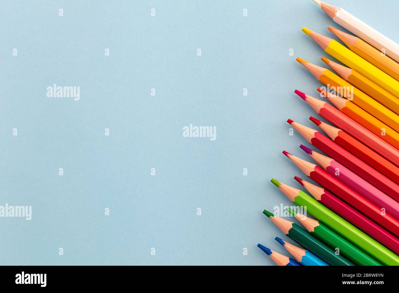 a selection of rainbow coloured pencils placed in a line from dark to light Stock Photo