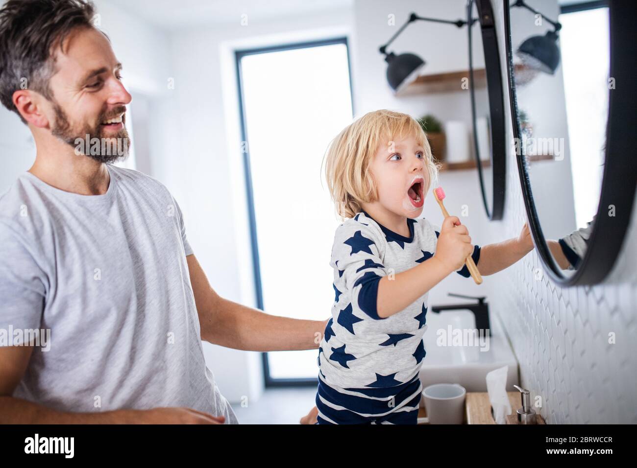 Mature father with small son indoors in bathroom, brushing teeth. Stock Photo