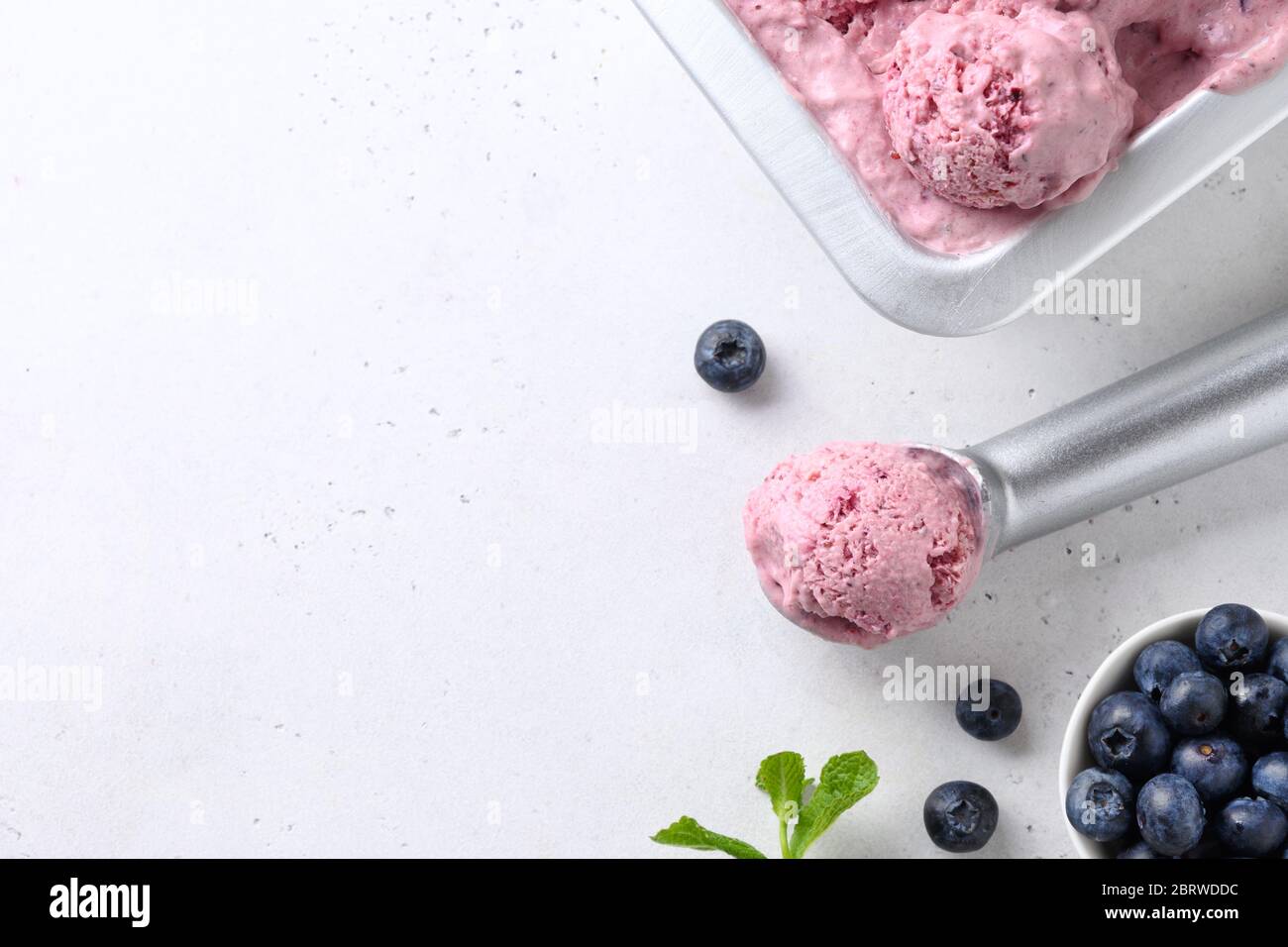 Bluberry and banana homemade ice cream or sorbet ball in scoop on white background. Close up. Space for text. Stock Photo