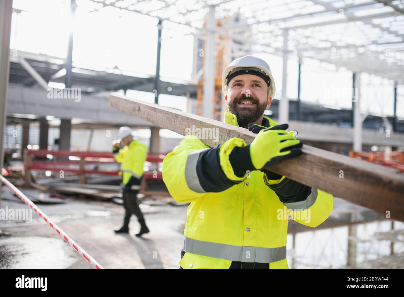 Men workers walking outdoors on construction site, working. Stock Photo
