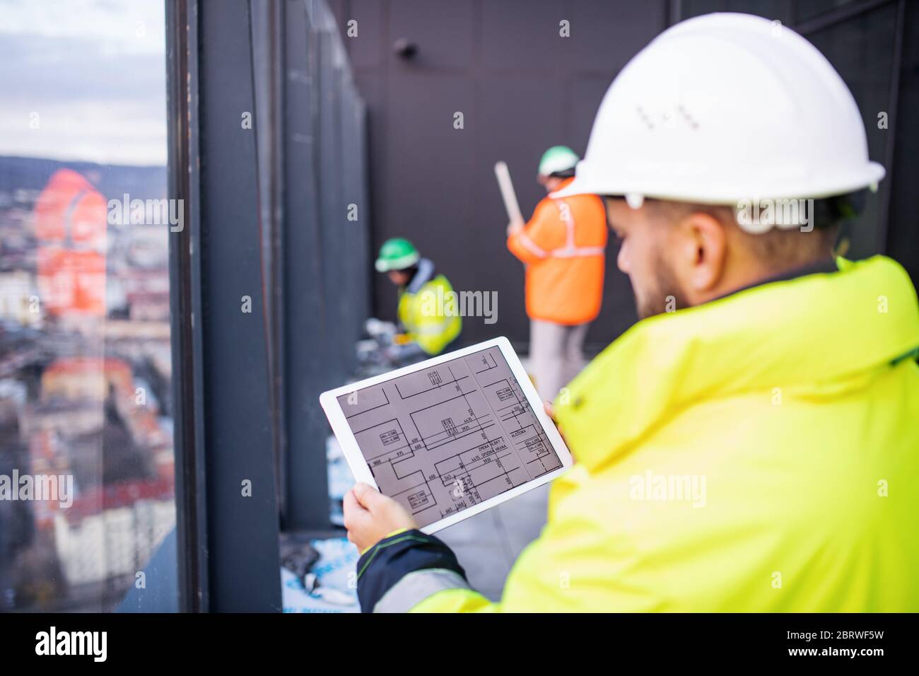 Man engineer standing on construction site, holding tablet. Stock Photo