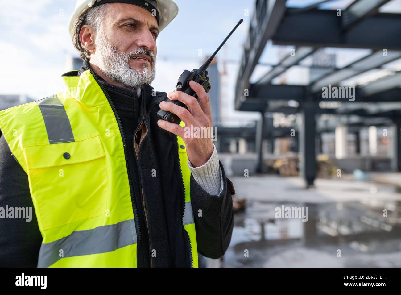 Man engineer using walkie talkie on construction site. Stock Photo