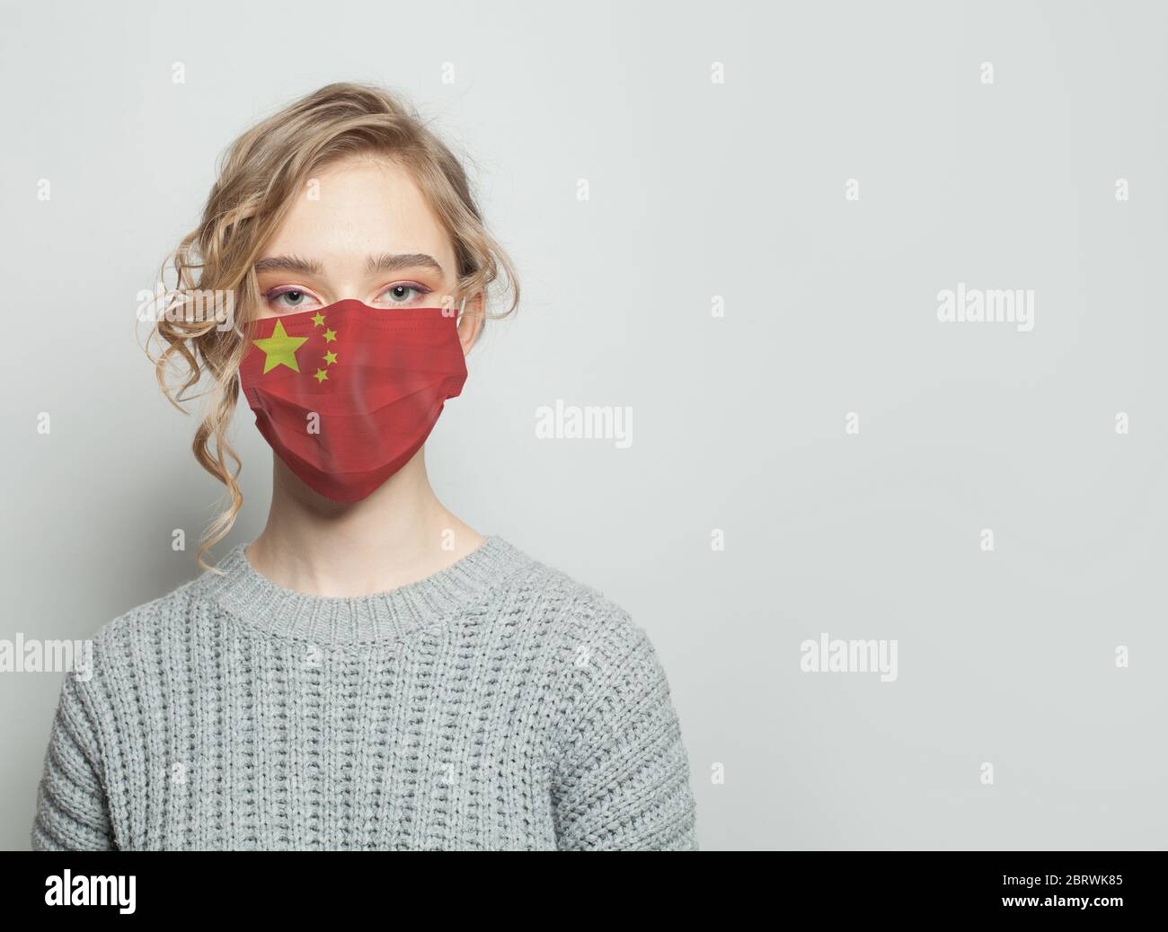 Young woman wearing a face mask with national flag China. Flu epidemic and virus protection concept Stock Photo